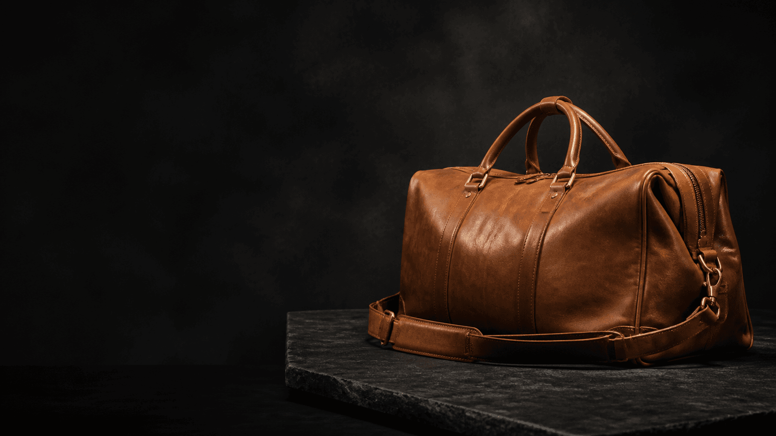 Caramel leather weekender in a dark studio